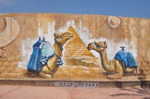 Decorative camel carvings against a yellow wall