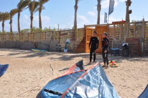 People beside a wooden beach entrance lined with palm trees