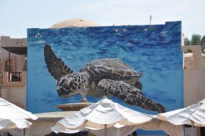 Carved turtle beside a sea-themed wall mural